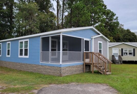 outside view of the zack flower manufactured home. Blue exterior, sitting on green grass.