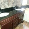 A bathroom vanity with double sinks and wooden cabinets.