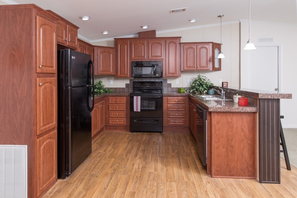 The Riley model's kitchen featuring wooden cabinets and black appliances