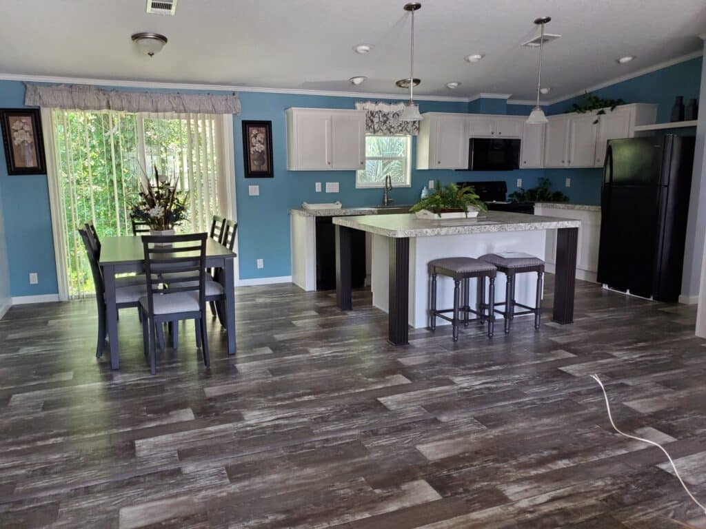 A kitchen containing a kitchen island with additional seating as well as counter space. The dining room is connected with a dining table.